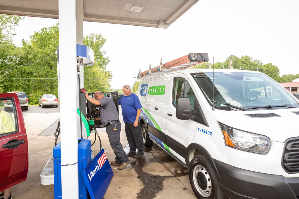 professional photo of two fuel service technicians checking fuel pump at convenience store.